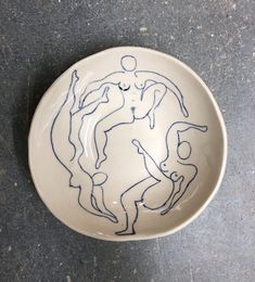 a bowl with a drawing on it sitting on the ground next to a wall and floor