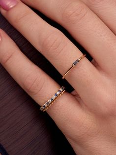 a woman's hand wearing a gold ring with blue and white stones on it