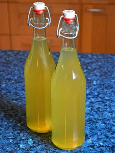 two glass bottles filled with yellow liquid sitting on top of a blue granite countertop