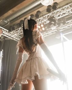 a woman in white dress standing on stage with her hands behind her back and legs spread out