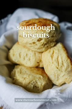 three biscuits stacked on top of each other in a white bowl with the words sourdough biscuits