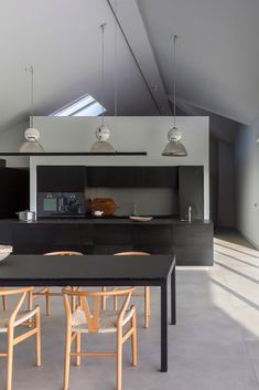 an open kitchen and dining area with black counter tops, white walls, and wooden chairs