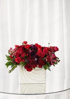 a white vase filled with red flowers on top of a table