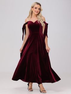 a woman wearing a long velvet dress with an off the shoulder bow at the waist