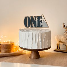 a white cake sitting on top of a table next to a deer figurine