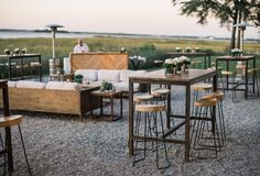 an outdoor seating area with wooden tables and stools set up for a wedding reception