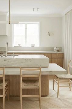 a kitchen with white counter tops and wooden chairs