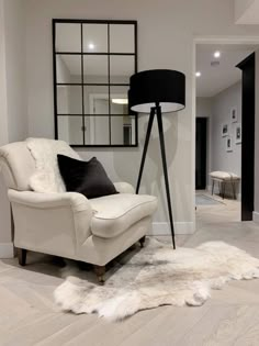 a white chair sitting on top of a hard wood floor next to a mirror in a living room