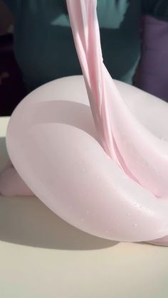 a pink object is blowing in the wind on top of a white table with purple pillows