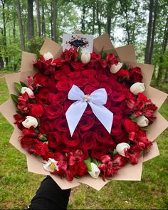 a bouquet of red roses and white tulips with a bow tied around it