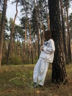 a person leaning against a tree in the woods