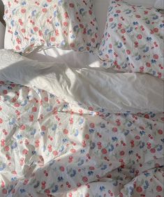 an unmade bed with floral sheets and pillowcases on top of each other