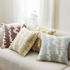 four pillows on a couch in front of a window