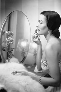 a woman is sitting in front of a mirror brushing her teeth