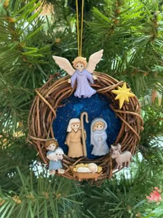 a nativity ornament hanging from a christmas tree