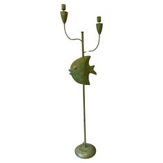 a green metal fish lamp with two candles on it's head and one arm