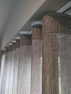 the curtains are lined up on the ceiling in front of the window sill, which is covered with burlap