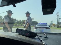 two police officers standing in front of a car