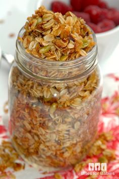 a jar filled with granola sitting on top of a red and white table cloth