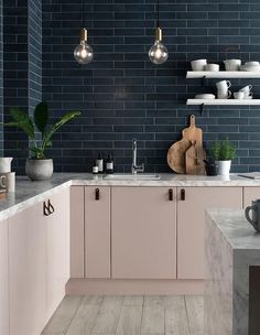 a kitchen with marble counter tops and pink cabinets, along with hanging lights above the sink