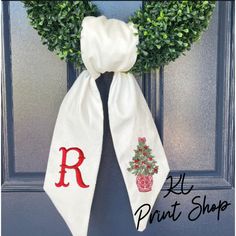 a door hanger with a christmas wreath and monogrammed ribbon hanging on it