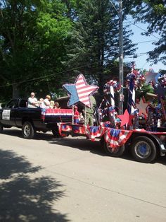 a parade float with people in the back and stars on the side, along with other floats