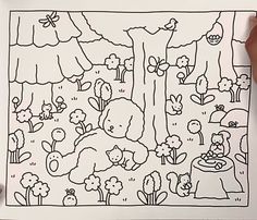 a person holding up a coloring book with animals and trees on it in front of them