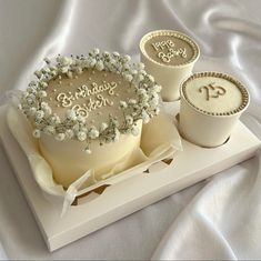 there is a cake and two cups on the trays that are decorated with baby's breath flowers