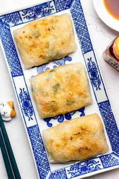 two rolls on a blue and white plate with chopsticks next to it,