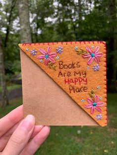 a hand holding up a piece of felt with the words books are my happy place on it