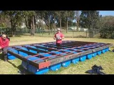 two men in red shirts standing next to a large blue and black trampoline