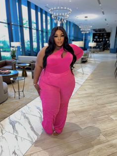 a woman in pink jumpsuits standing on the floor next to a large chandelier