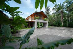 the house is surrounded by lush vegetation and palm trees, with an open patio area