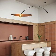 three white stools sitting in front of a wooden counter with two vases on it