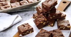 chocolate fudge brownies stacked on top of each other in front of a baking pan