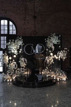 a large display with flowers and candles in front of a brick wall that reads m