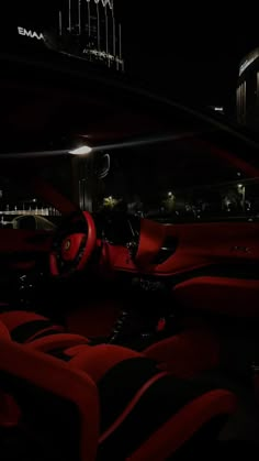 the interior of a car with red leather seats and black flooring at night time