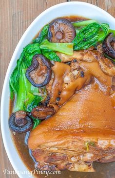 a white bowl filled with meat and veggies on top of a wooden table