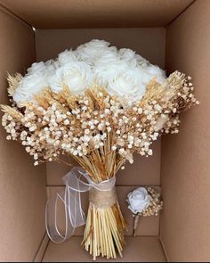 a bouquet of white roses in a cardboard box with some ribbon on the side and a bow tied around it