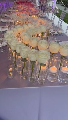 the table is set up with candles and flowers in vases for centerpieces