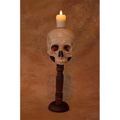 a candle that is sitting on top of a wooden pole with a skull head in the middle