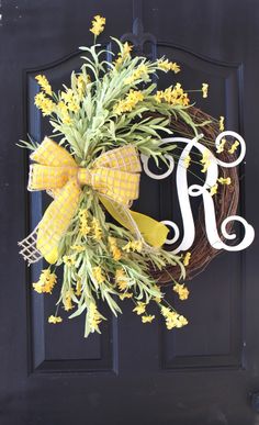 a yellow wreath with the letter s on it is hanging from a black front door