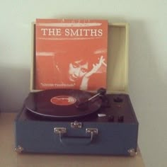 a record player sitting on top of a suitcase next to an orange sheet music album