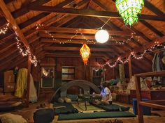 a man sitting on top of a yoga mat in a room with lights hanging from the ceiling