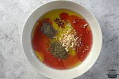 a white bowl filled with lots of different types of food in liquid and seasoning