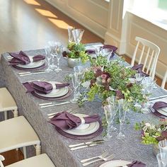 the table is set with silverware and purple napkins