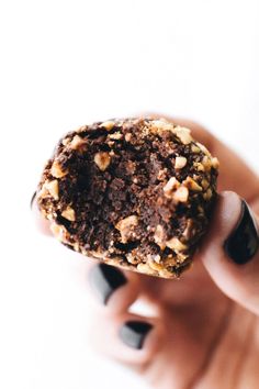 a close up of a person holding a doughnut in their hand with walnuts on top