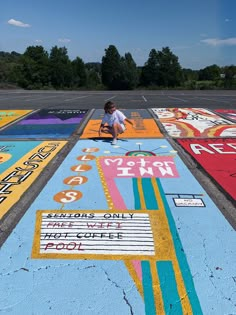 a person kneeling on the ground in front of painted parking spaces