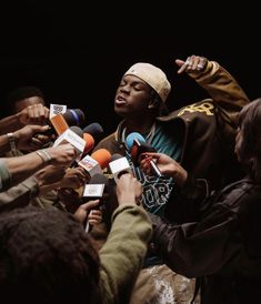 a man is surrounded by reporters and microphones