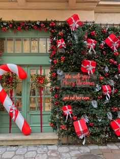 christmas decorations and gifts are on display in front of a storefront with large candy canes